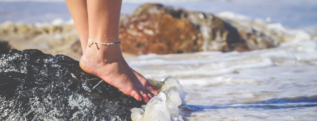 to ground yourself stand barefoot woman standing on rock near the waves