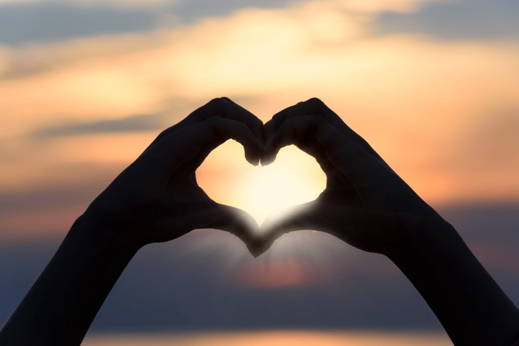 showing fingers and hand shaped like a heart to express abundance energy